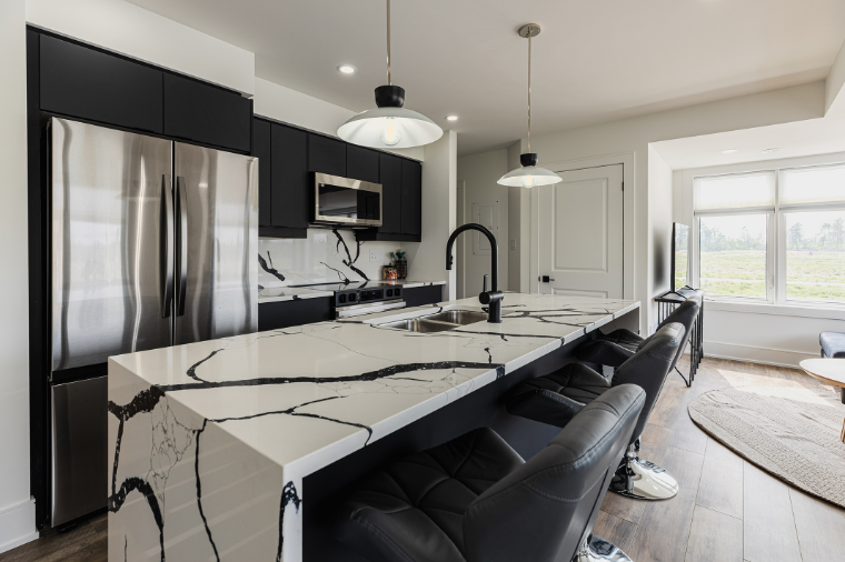 Mira model home kitchen — dramatic white marble island with black cabinetry and stainless appliances